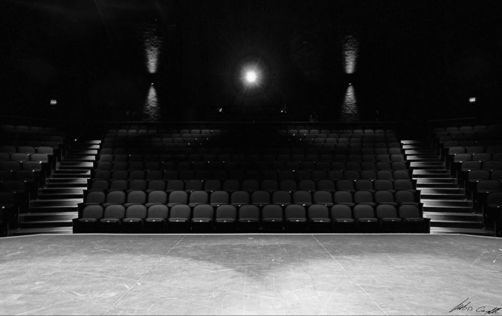 Empty theatre stage bathed in warm light, awaiting an audience